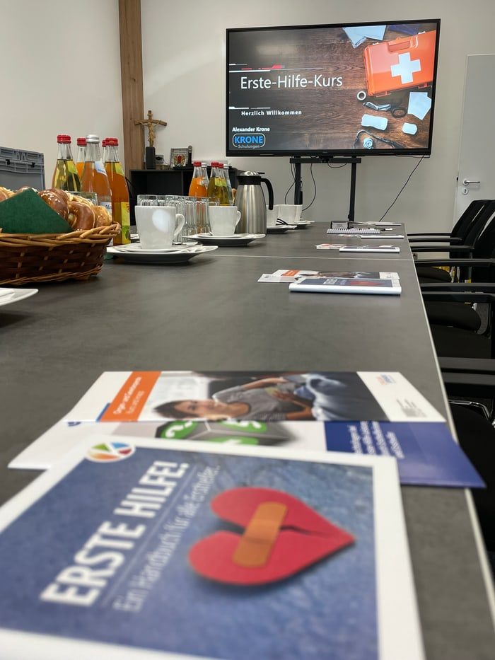 Präsentationstafel mit Erste-Hilfe-Kurs Informationen und Materialien auf einem Tisch.