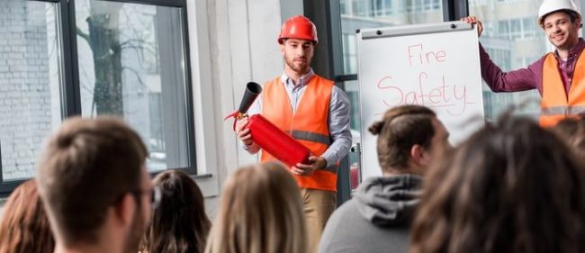 Schulung zur Brandsicherheit mit Feuerlöscher Zwei Personen in Sicherheitswesten präsentieren einen Feuerlöscher während einer Brandschutzschulung.